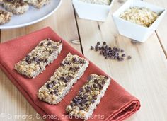 homemade granola bars on a red napkin with chocolate chips and oats in the background