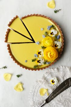 there is a yellow cake with flowers on the top and a knife next to it