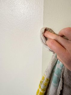 a hand is pulling up the edge of a white wall with towels hanging on it