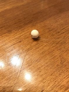 a white ball sitting on top of a wooden table next to a light brown surface