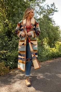 Wyeth Trail Long Coat Our long Wyeth Trail coat will keep you covered from top to bottom.  Made from the Pendleton® Wyeth Trail wool blanket, the warm earth tone colors are easy to wear.  Wear it open or close at the waist with a toggle.  Designed for a slightly oversized fit and look.   The Wyeth Trail blanket reflects warm, harmonious colors of ancient corn varieties patterned in rows similar to ancient Native American gardens.  Arrows point in two directions, the past and the future.  Model is 5'9", 140 lbs, wearing size medium Blanket weight, shawl collar.  S, M, L 82% pure virgin wool / 18% cotton, woven in the USA Approx 46" back length from collar Dry clean only Made in the USA Flat Lay measurements:  Small:  Chest - 22"   Sleeve length from shoulder - 25" (unrolled) Bicep - 7.5" Sh Corn Varieties, Pixie Mood Handbags, Future Model, Pendleton Blanket, American Garden, 140 Lbs, Upcycled Bag, Blanket Coat, Earth Tone Colors