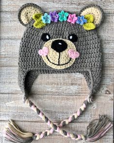 a crocheted bear hat with flowers on it's head and ears is shown