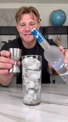 a man is holding a bottle and ice cubes in front of him