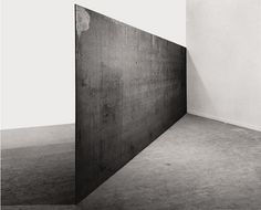 a black and white photo of an empty room with a large piece of wood on the floor