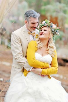 a bride and groom smile as they stand in the woods