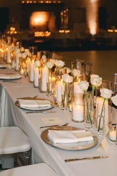 a long table is set with white flowers and candles