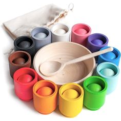 the wooden spoon is next to many different colored cups