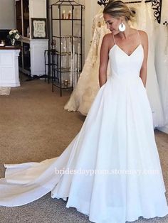 a woman standing in front of a mirror wearing a white wedding dress with spaghetti straps