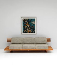 a couch sitting in front of a painting on the wall next to a wooden table