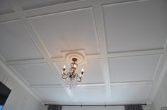 a chandelier hanging from the ceiling in a room with white walls and curtains