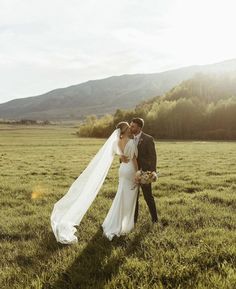 a bride and groom standing in the middle of a field