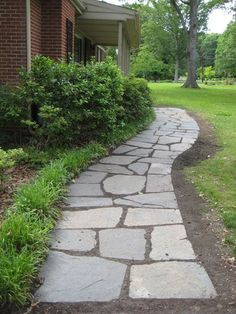 a stone path in front of a brick house