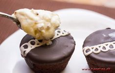 two chocolate cupcakes with white frosting and a spoon