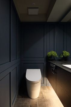 a white toilet sitting inside of a bathroom next to a sink and counter top under a mirror