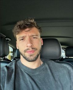 a man sitting in the back seat of a car with his eyes closed and looking at the camera