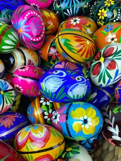 many colorful painted eggs are stacked on top of each other