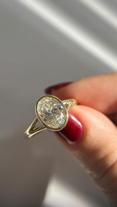 a woman's hand holding a yellow gold ring with a diamond in the middle