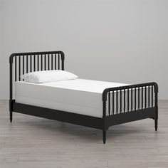 a black bed frame with white sheets and pillows on top of it, against a gray wall