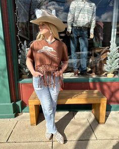 Featuring short sleeves and a solid chocolate brown design, the Miss Me Women's Brown Cowgirl Hat Fringe Tee Shirt is the perfect addition to any cowgirl's wardrobe. Complete with fringe accents on the trim, studded details on the front, and a "Dibs On The Cowboy" graphic with a cowboy hat, this tee exudes western charm. Its rib knit crew neck adds a touch of comfort to this stylish and eye-catching piece. Gentle machine was with like colors in cold water Tumble dry low Western Style Brown Tops For Ranch, Country Style Short Sleeve Tops For Western-themed Events, Brown Western Style Summer Tops, Fitted Short Sleeve Tops For Country Events, Fitted Country Style Short Sleeve Tops, Casual Short Sleeve Tops For Country Events, Western Style Short Sleeve Tops For Rodeo, Casual Brown Tops For Western-themed Events, Brown Fringe Tops For Fall