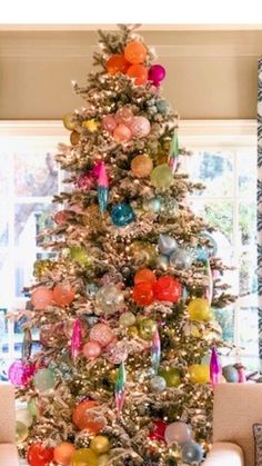 a decorated christmas tree in a living room with colorful ornaments on the top and bottom