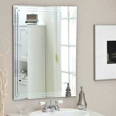 a bathroom sink sitting under a mirror next to a white cabinet and wall mounted faucet