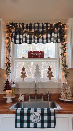 a kitchen sink under a window decorated with christmas trees and garlands on the windowsill