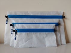 three blue and white zippered bags sitting on top of a table