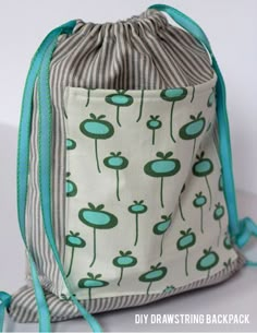 a drawstring bag with blue and green flowers on the front is sitting on a white surface