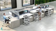 an office cubicle with three people working at desks and two monitors on the wall