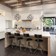 a kitchen island with four stools in front of it and lights hanging from the ceiling