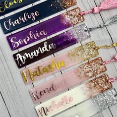 six name tags with tassels on them sitting on a wooden table next to each other