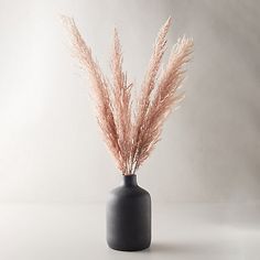 some pink flowers in a black vase on a white tableclothed surface with grey background