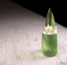 a tall glass filled with green liquid on top of a table