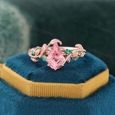 a pink diamond ring sitting on top of a blue cushion