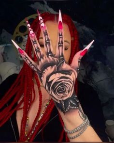 a woman with red dreadlocks holding her hand up to the camera