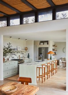 an open kitchen and dining area with wood flooring, white cabinets and counter tops