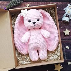 a pink crocheted teddy bear sitting in a box on a table next to other items