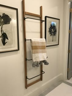 a towel rack in the corner of a bathroom with pictures on the wall behind it