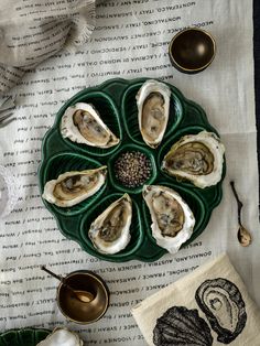 a green plate topped with oysters on top of a table