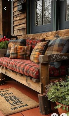 a wooden bench sitting on top of a porch next to flowers and potted plants