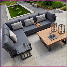 an outdoor living room with grey couches and coffee table in front of a pond