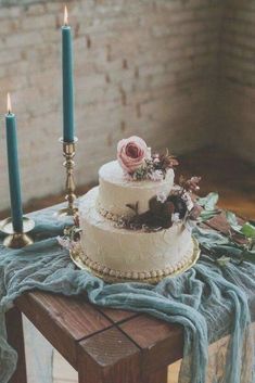 a three tiered wedding cake on a table with two candles