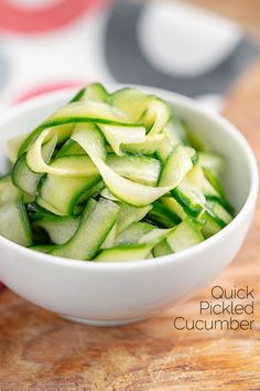 a white bowl filled with cucumbers on top of a wooden table