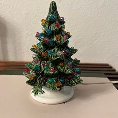 a small christmas tree sitting on top of a white table next to a light bulb