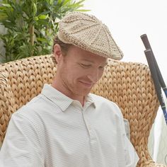 a man sitting in a wicker chair reading a book and holding a baseball bat