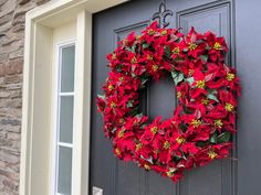 a wreath is hanging on the front door of a house decorated with poinsettis