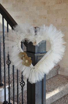 a heart shaped wreath on top of a black post in front of a stair case