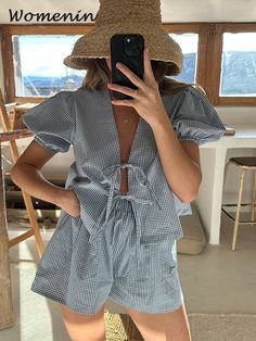 a woman taking a selfie while wearing a straw hat and blue gingham rom