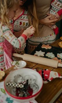 a woman and child are making christmas cookies