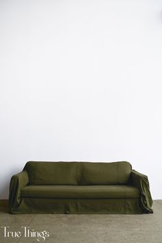 a green couch sitting in front of a white wall